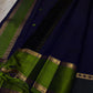 Deep midnight indigo Kanchipuram silk body with spaced green paisley-floral buttas and tiny magenta accents.