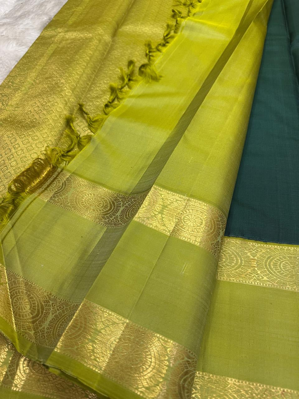 Deep forest-green Kanchipuram silk body showing sparse silver-toned maanga and leaf-style woven buttas.