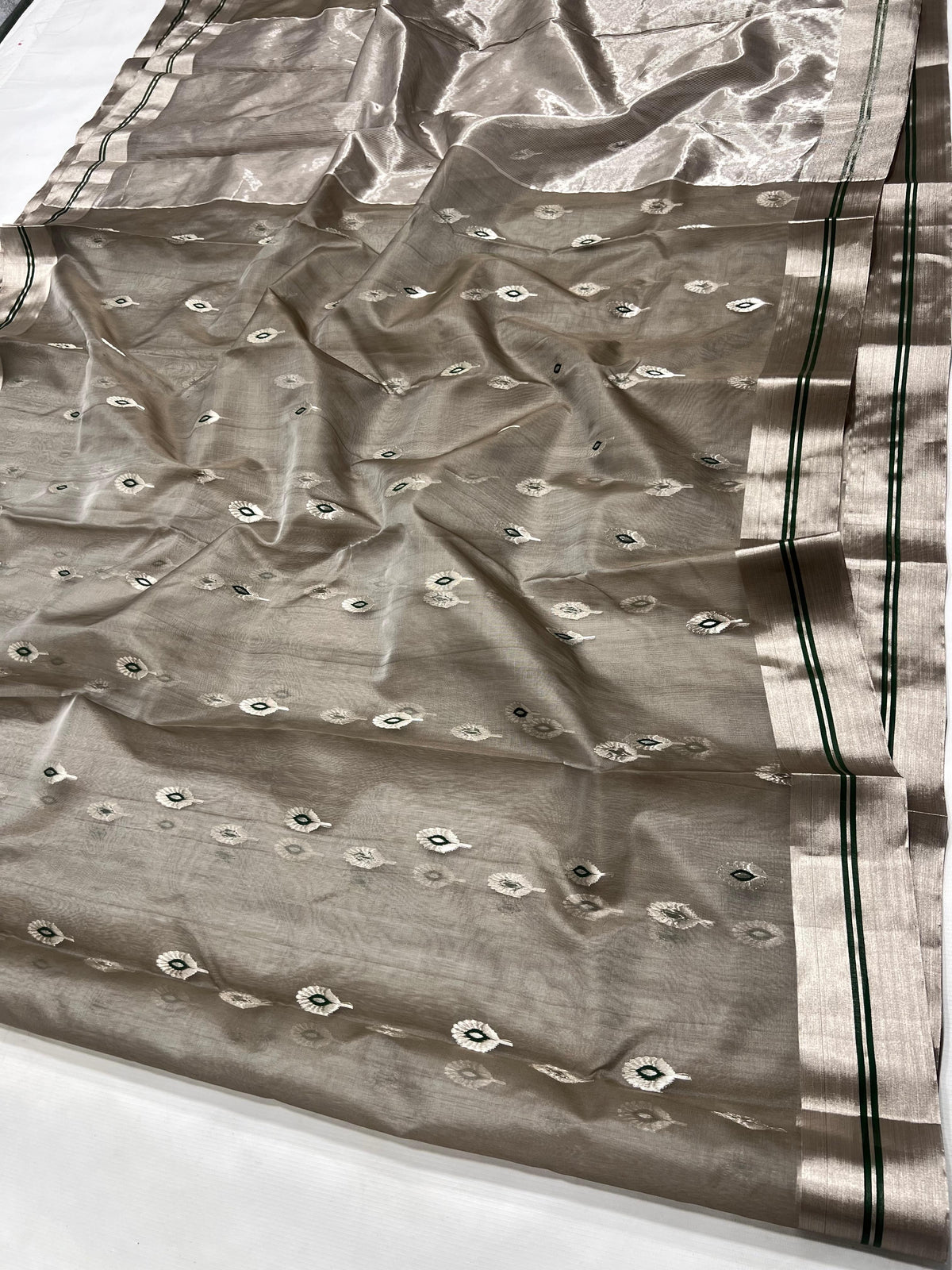 Close-up of silver-tone feather motifs with Emerald Green centres on the Stone Grey Katan Silk Chanderi saree.