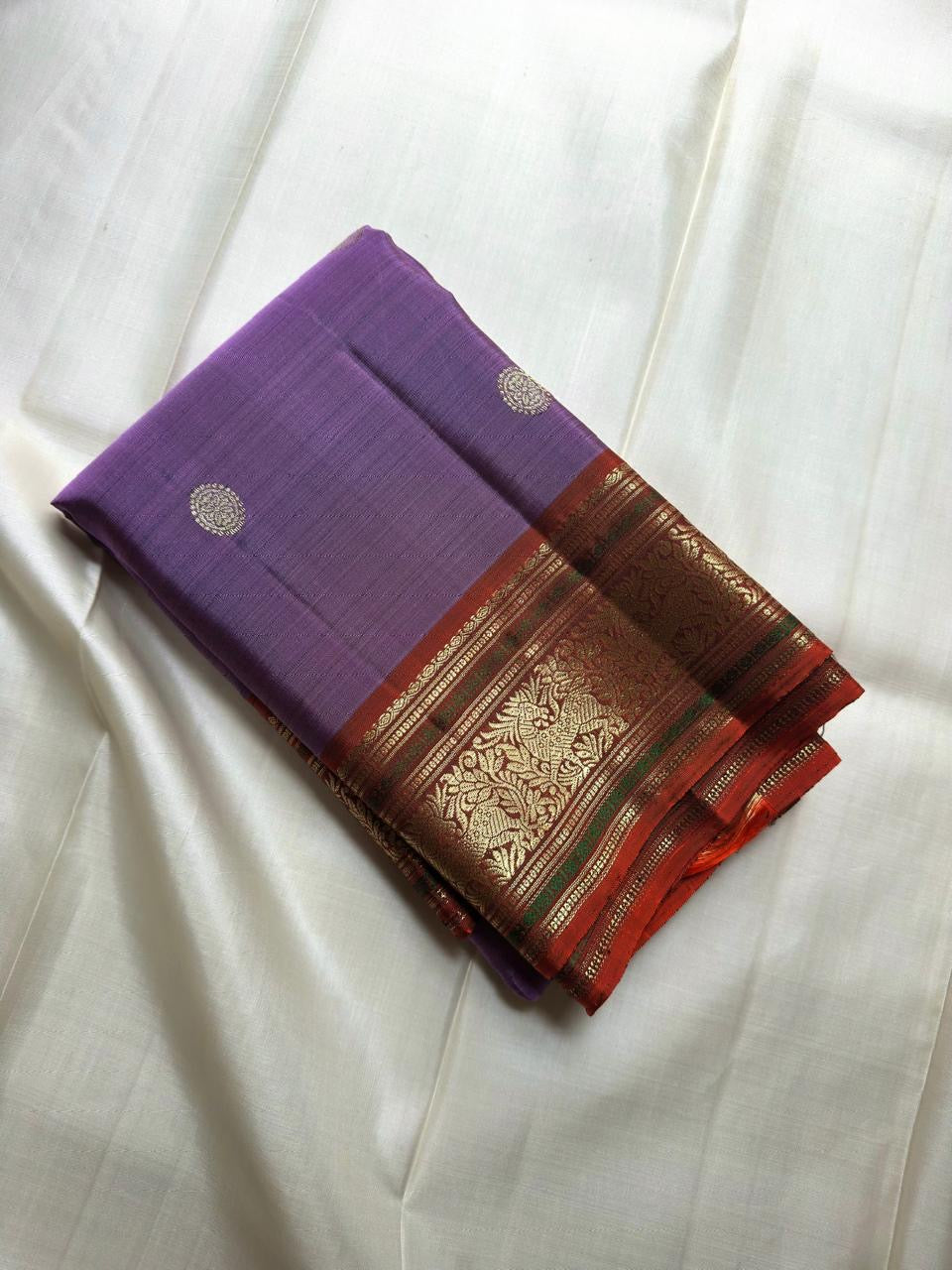 Soft lavender-purple Kanchipuram silk body scattered with understated traditional classic-gold zari buttas.