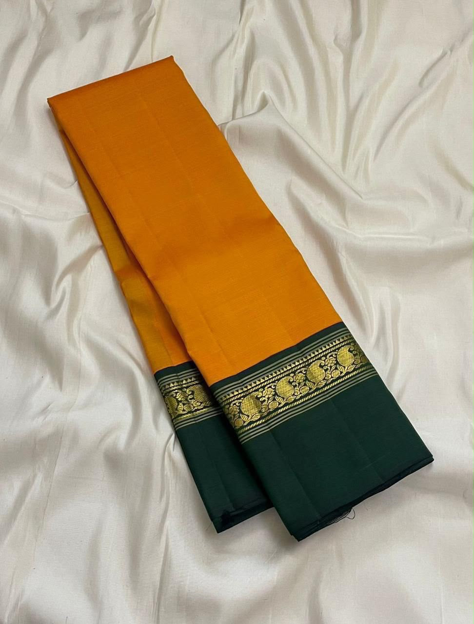 Handwoven saffron gold Kanchipuram silk saree with deep green contrast Korvai border and zari detailing