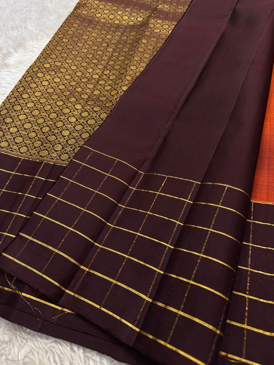 Small spaced golden motifs woven across the vivid terracotta-orange Kanchipuram silk body