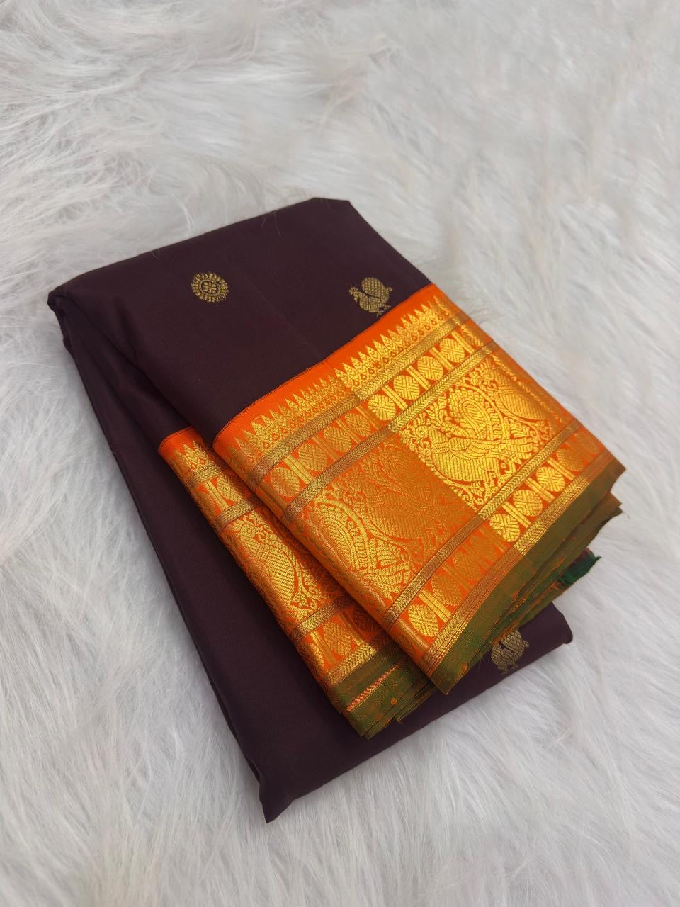 Detail of Kesari orange Kanchipuram border with layered gold zari and traditional peacock ornament.
