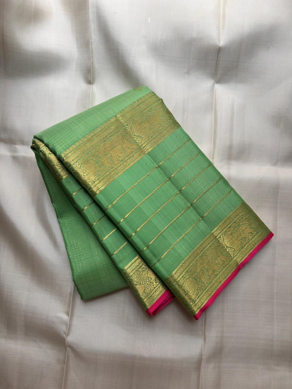 Kili Pachai green border with floral-vine and geometric gold-zari registers along the silk edge.