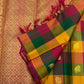 Checked Kanchipuram silk showing green, yellow, olive and pink squares with warm gold zari woven details.