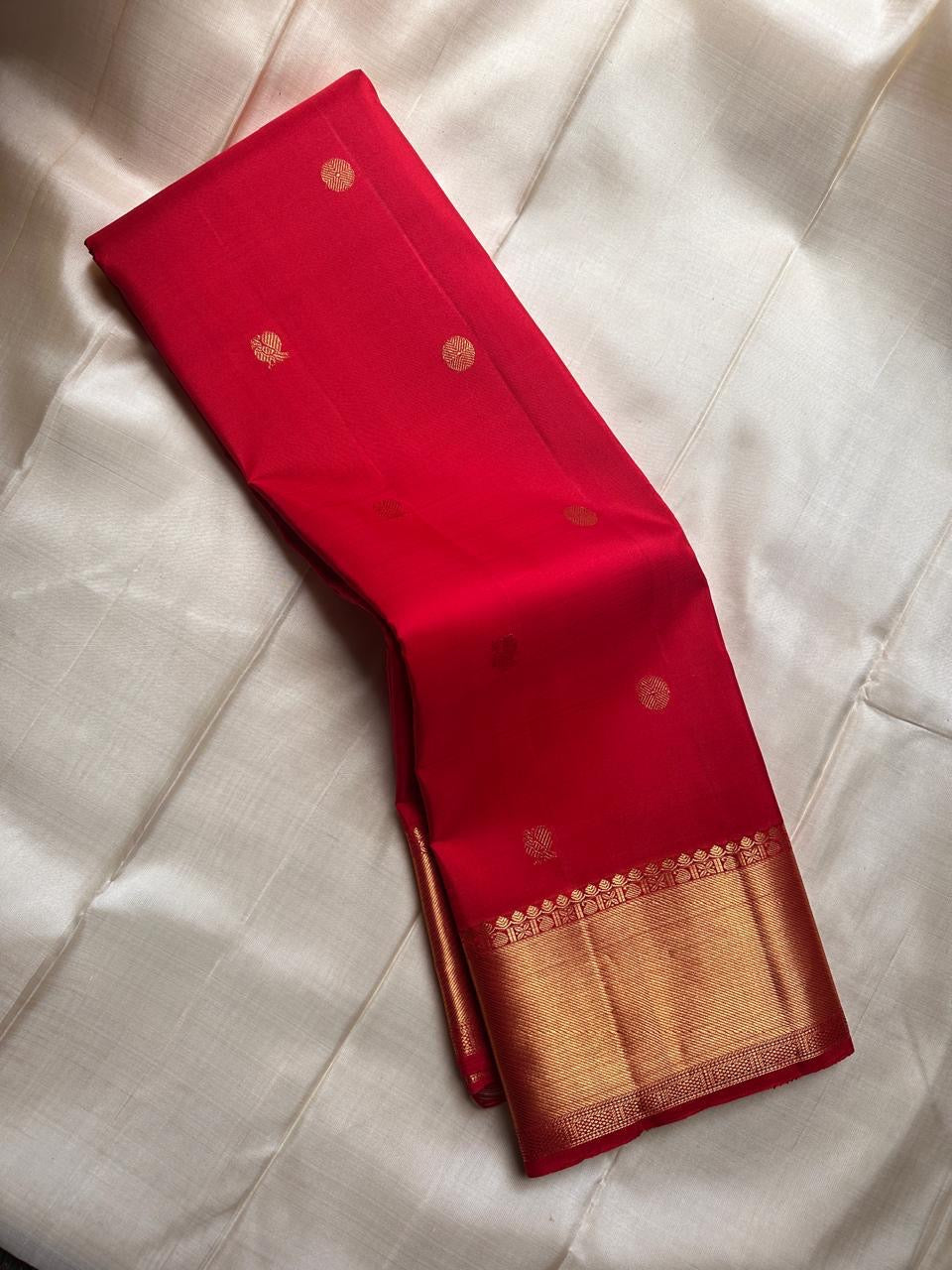 Pure silk Kanchivaram saree with delicate zari buttas woven across a vibrant red body