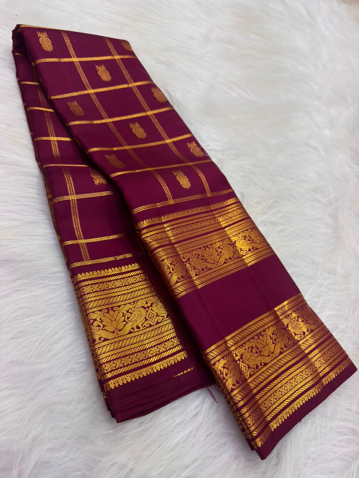 Deep lac-maroon handwoven Kanchipuram silk showing fine gold Kattam structure and traditional body buttas.