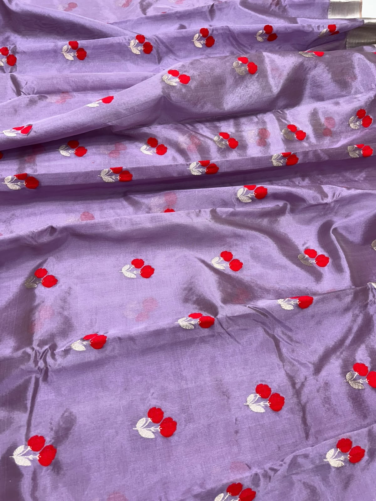 Close-up of bright red paired floral motifs with silver-toned leaves on lavender Chanderi silk