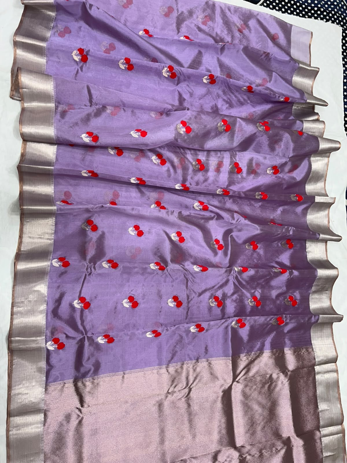 Delicate silver leaf motifs beside red flowers on purple silk