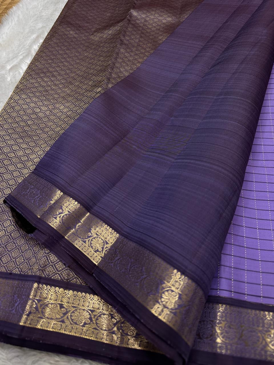 Deep plum pallu close-up with zari woven floral border and solid contrast panel