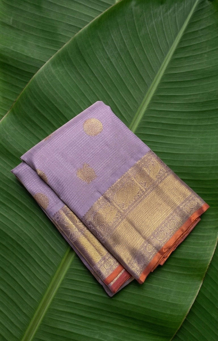 Kanchipuram silk saree in lavender mist with peach orange selvedge antique gold border border Zari Kattam weave folded view