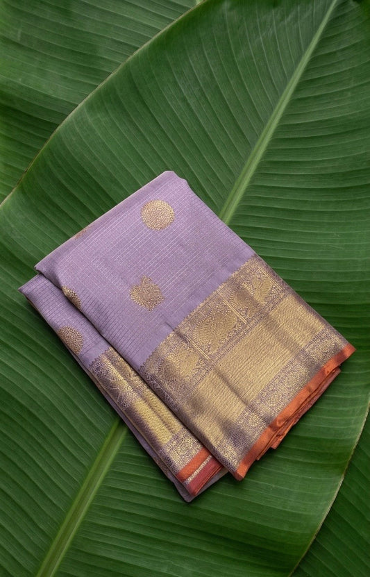 Kanchipuram silk saree in lavender mist with peach orange selvedge antique gold border border Zari Kattam weave folded view