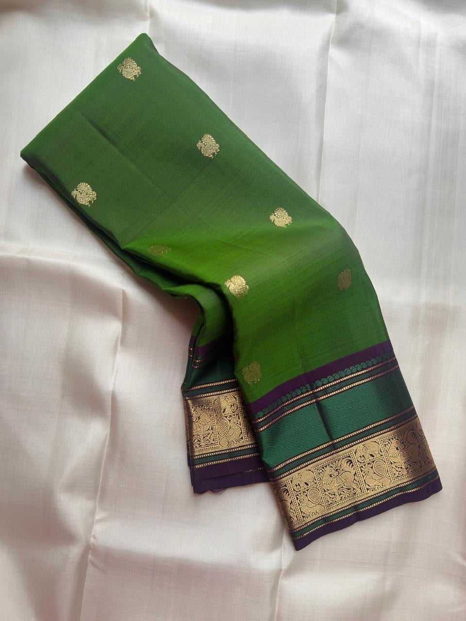 Close-up of antique gold zari Butta motifs on leaf green Kanjivaram silk saree