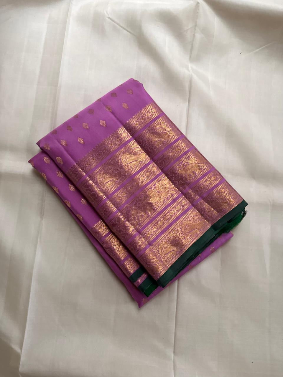 Lilac Kanchipuram silk saree with dark leaf-green edge, folded to show the Varisaipet border and pallu
