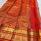 Detailed vermilion-red contrast border with ornamental kodi butta work and gold zari bands.