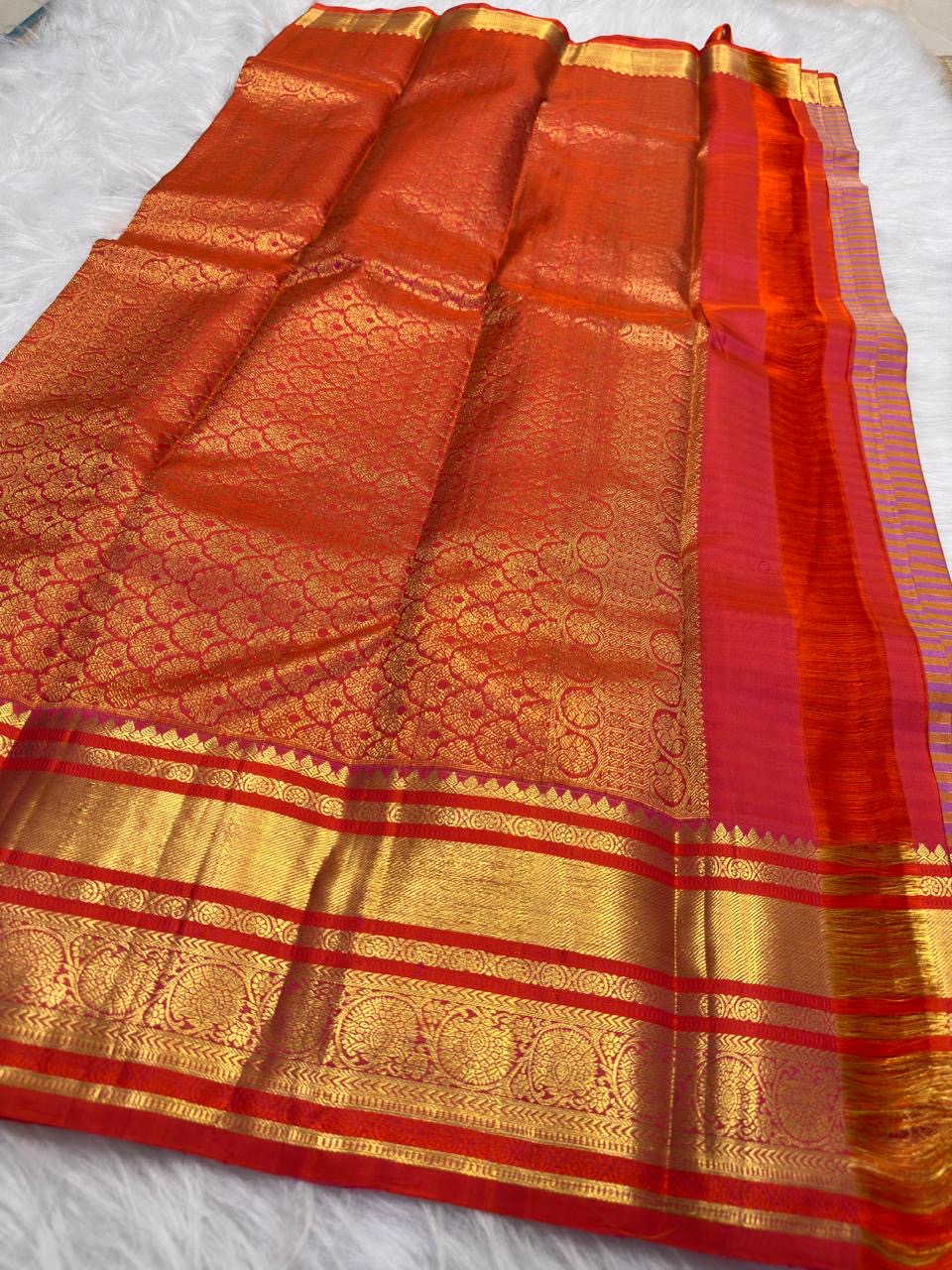Detailed vermilion-red contrast border with ornamental kodi butta work and gold zari bands.