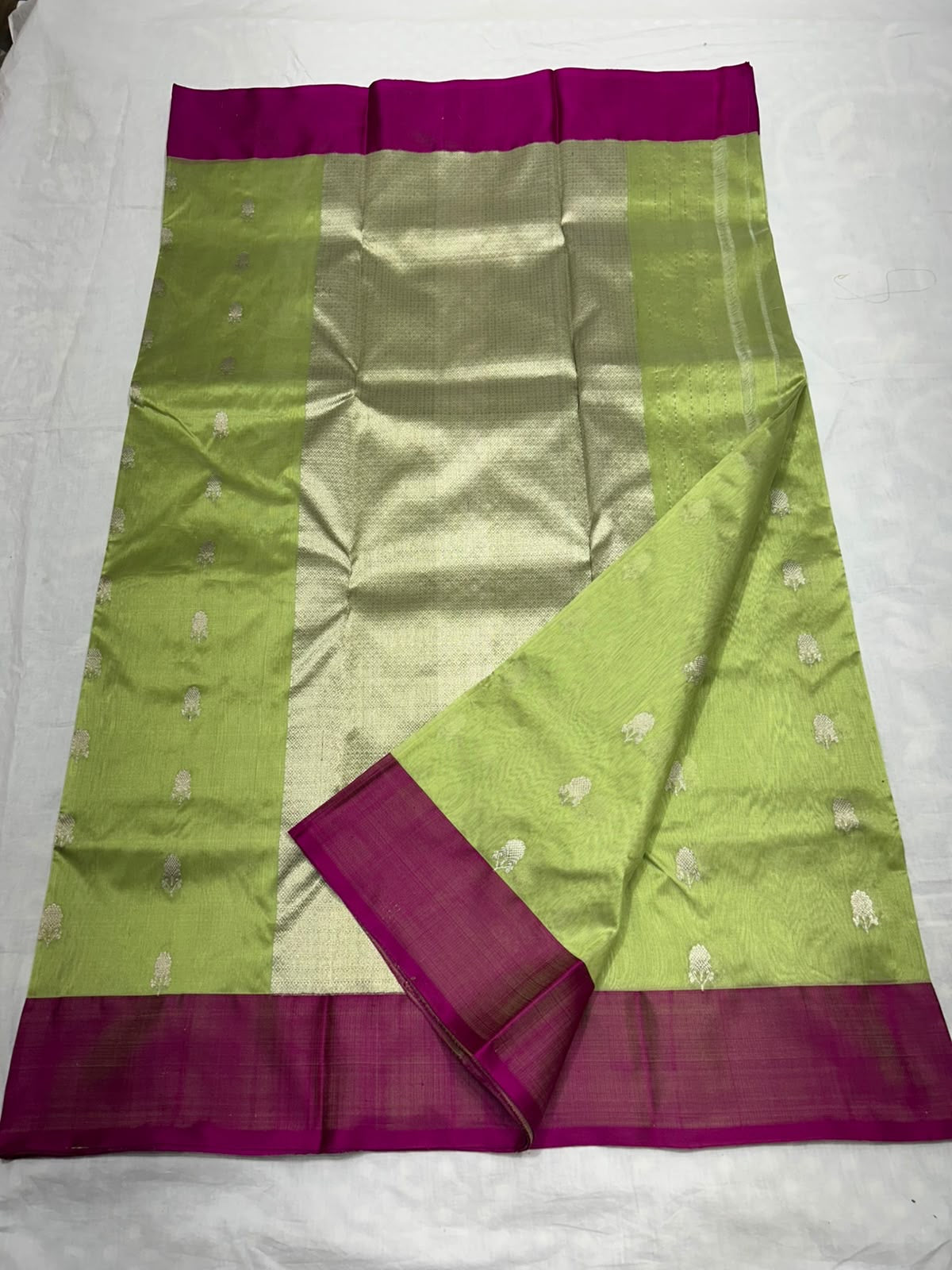 Close-up of small metallic floral buttas on a lime green Chanderi silk saree.