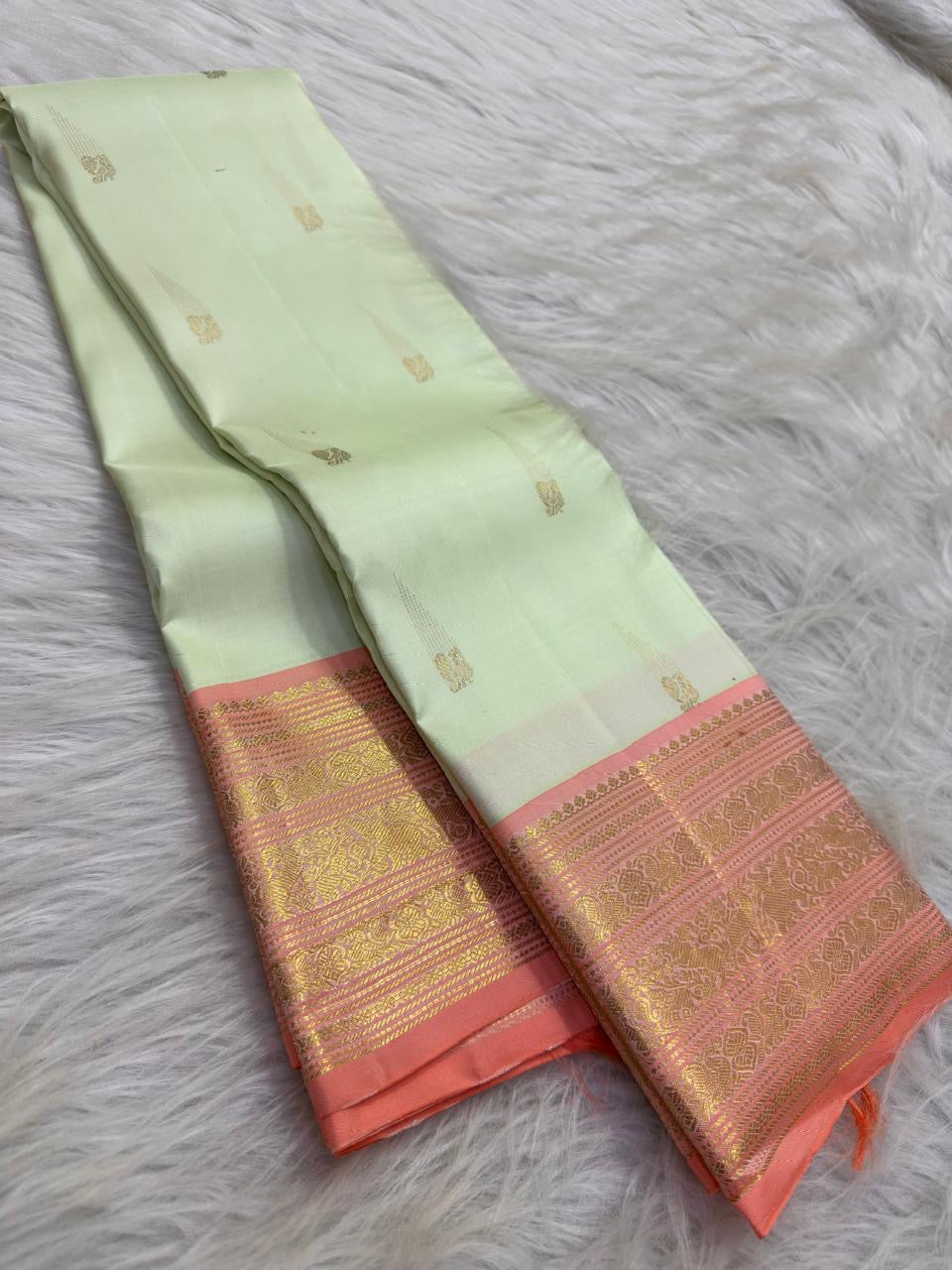 Peach contrast border showing fine geometric zari bands, ornamental registers and softly antique gold detailing.