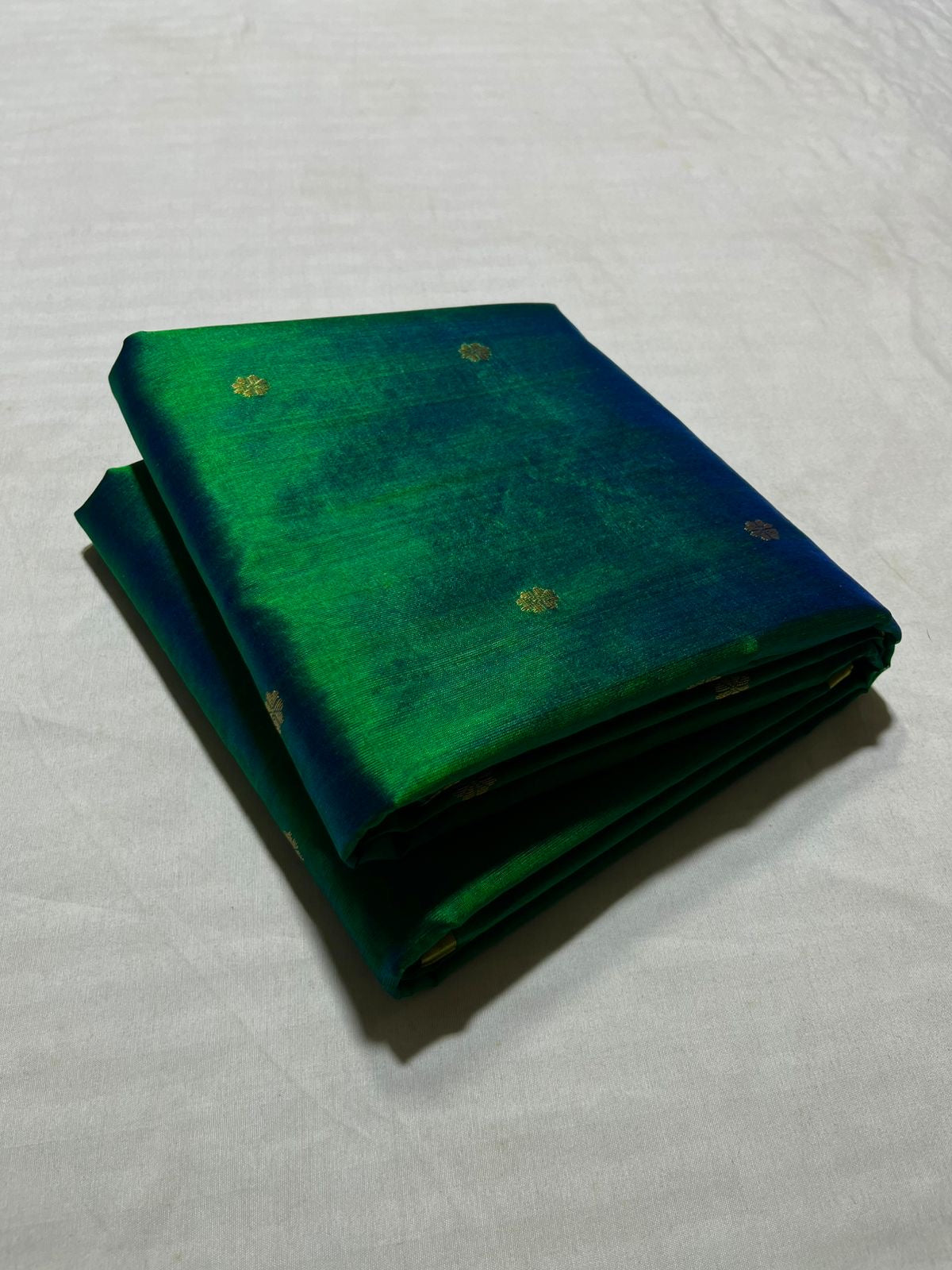 Peacock blue green pure silk Chanderi handloom saree with delicate zari buttas folded on neutral backdrop