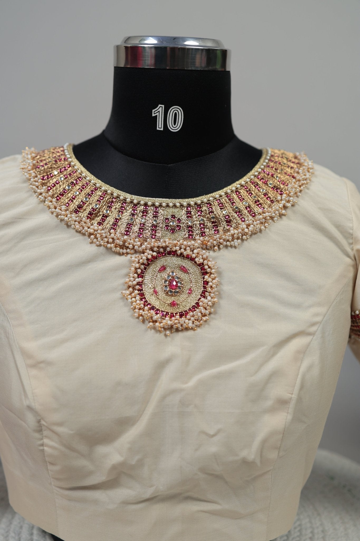Close-up of durable kemp stones and hand embroidery on cream silk blouse