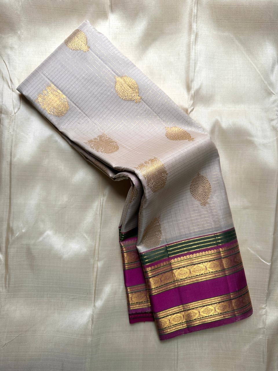 Pearl silver pure Kanchipuram silk saree draped to show gold paisley buttas and magenta zari border