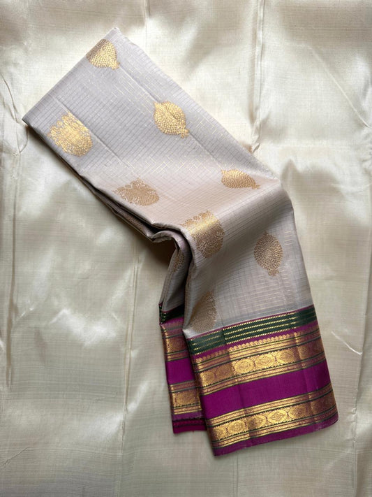 Pearl silver pure Kanchipuram silk saree draped to show gold paisley buttas and magenta zari border