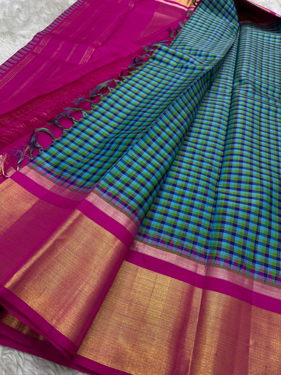 Folded checked Kanchipuram silk saree with magenta border and gold zari panel beside another folded saree on ivory backdrop