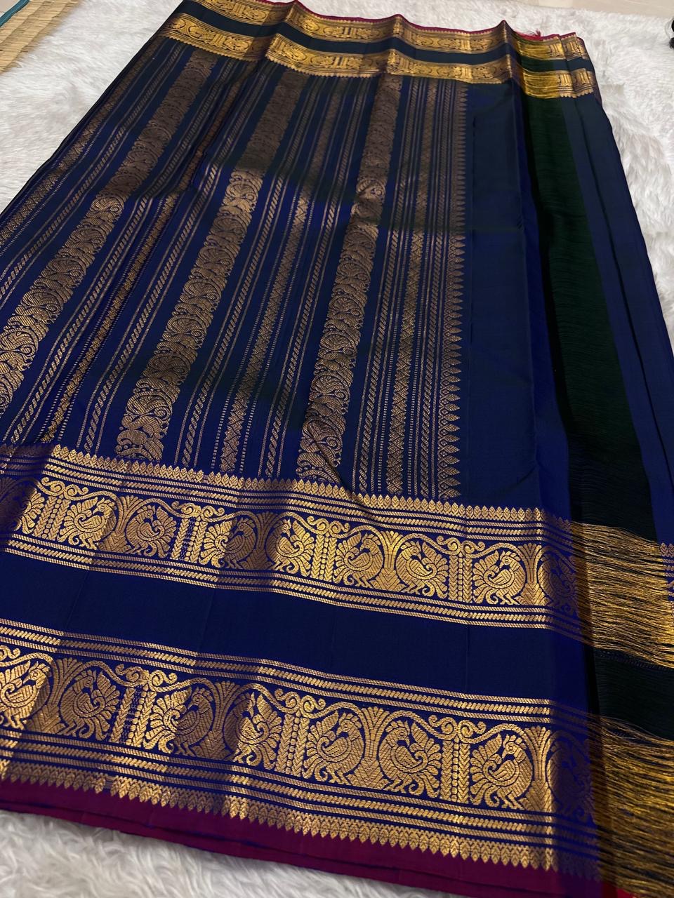 Navy blue Kanjipuram silk saree body close-up showing Mayil peacock and Pavun coin antique gold zari butta motifs
