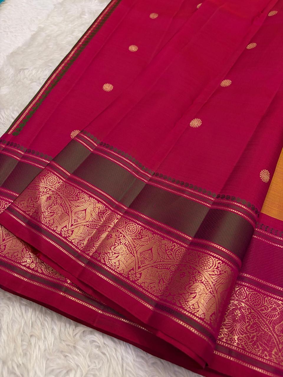 Vadamalli magenta pallu with circular gold buttas and a deep olive-green zari border