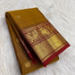 Folded Manjal gold pure silk Kanchipuram saree with spaced zari buttas and a deep Arakku Yazhi border.