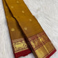 Burnished Manjal body showing open placement of figurative and floral thanga-zari buttas across the silk field.