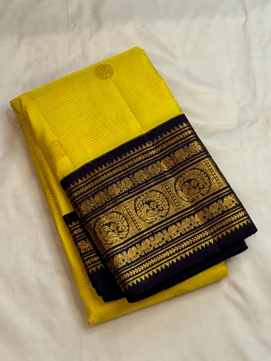 Full view of vivid manjal-yellow Vairaoosi silk with a deep navy and gold peacock border
