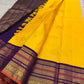 Handwoven radiant turmeric-flower manjal yellow contrasted with deep violet-purple Varisaipet pure silk Kanchipuram saree with rich zari border