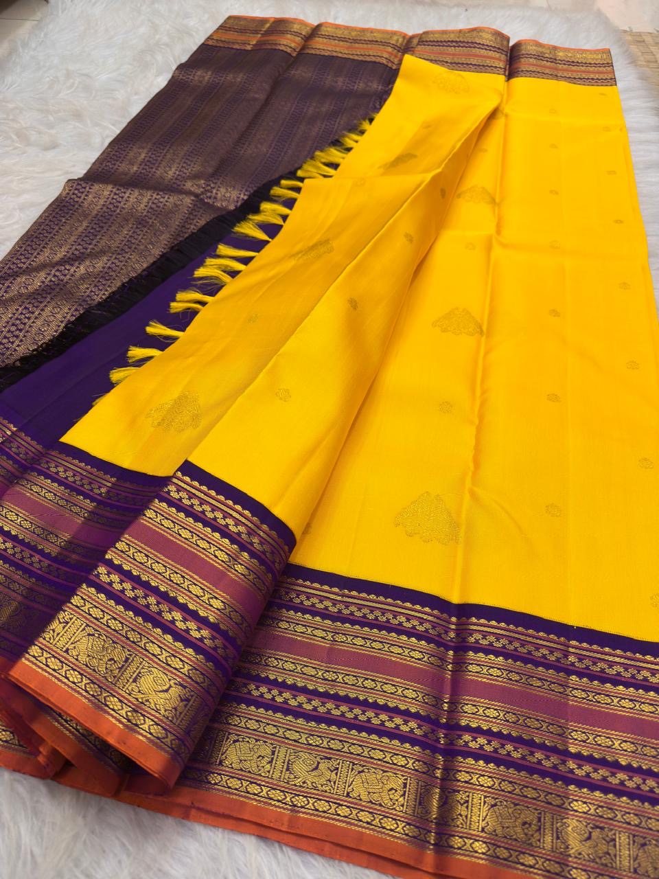 Handwoven radiant turmeric-flower manjal yellow contrasted with deep violet-purple Varisaipet pure silk Kanchipuram saree with rich zari border