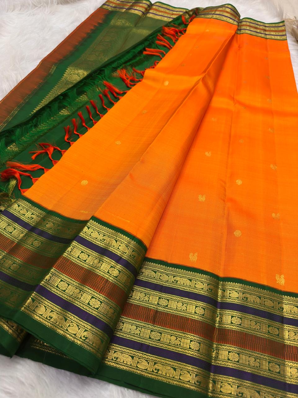Marigold orange Pure Silk Kanchipuram saree with green layered varisaipet border and petite zari buttas.