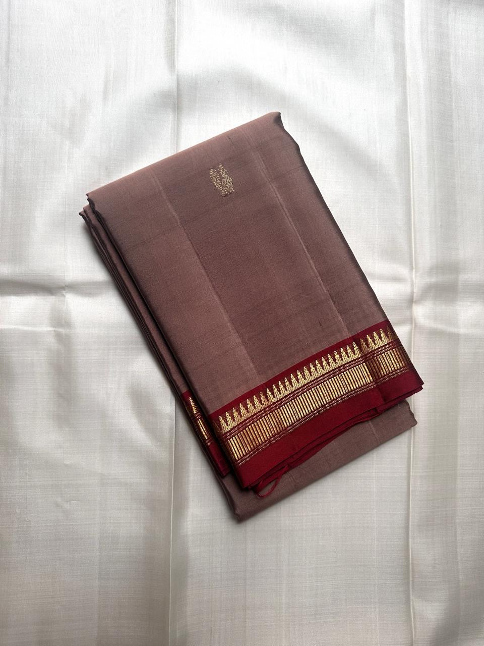 Pure Kanchipuram silk saree spread open showing maroon pallu with vertical zari panels and contrast beige body