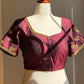 Purple blouse with gold embroidery on a mannequin against a neutral background
