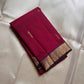 Folded deep maroon Pure Kanchipuram silk saree with small zari buttas and a gold zari woven border with dark edging.