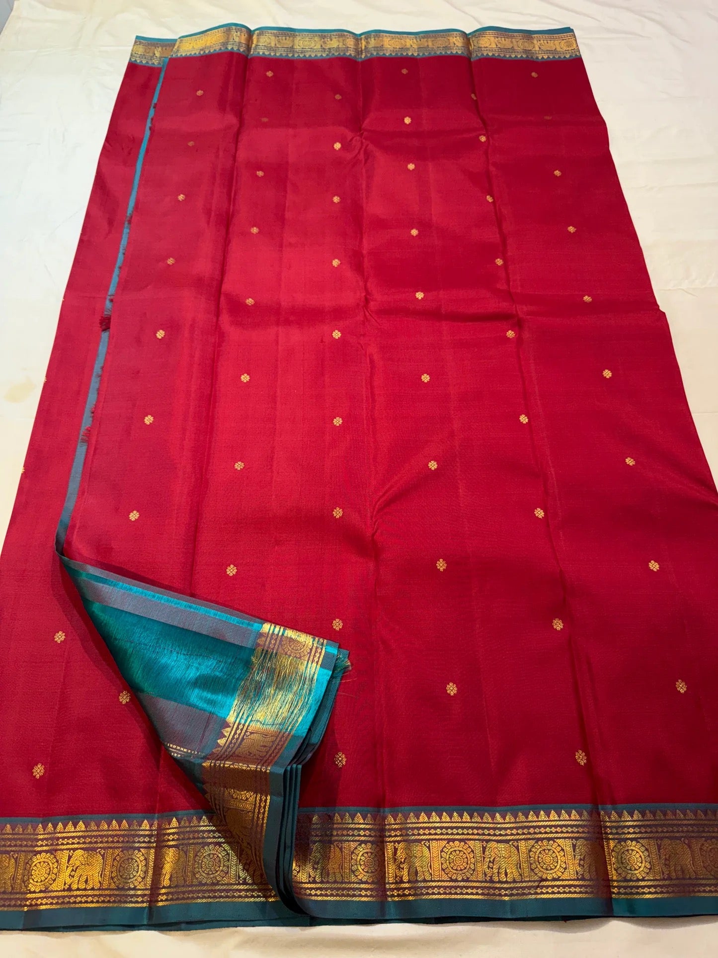 Teal petite border with gold elephant and chakra medallion band on maroon Kancheepuram saree