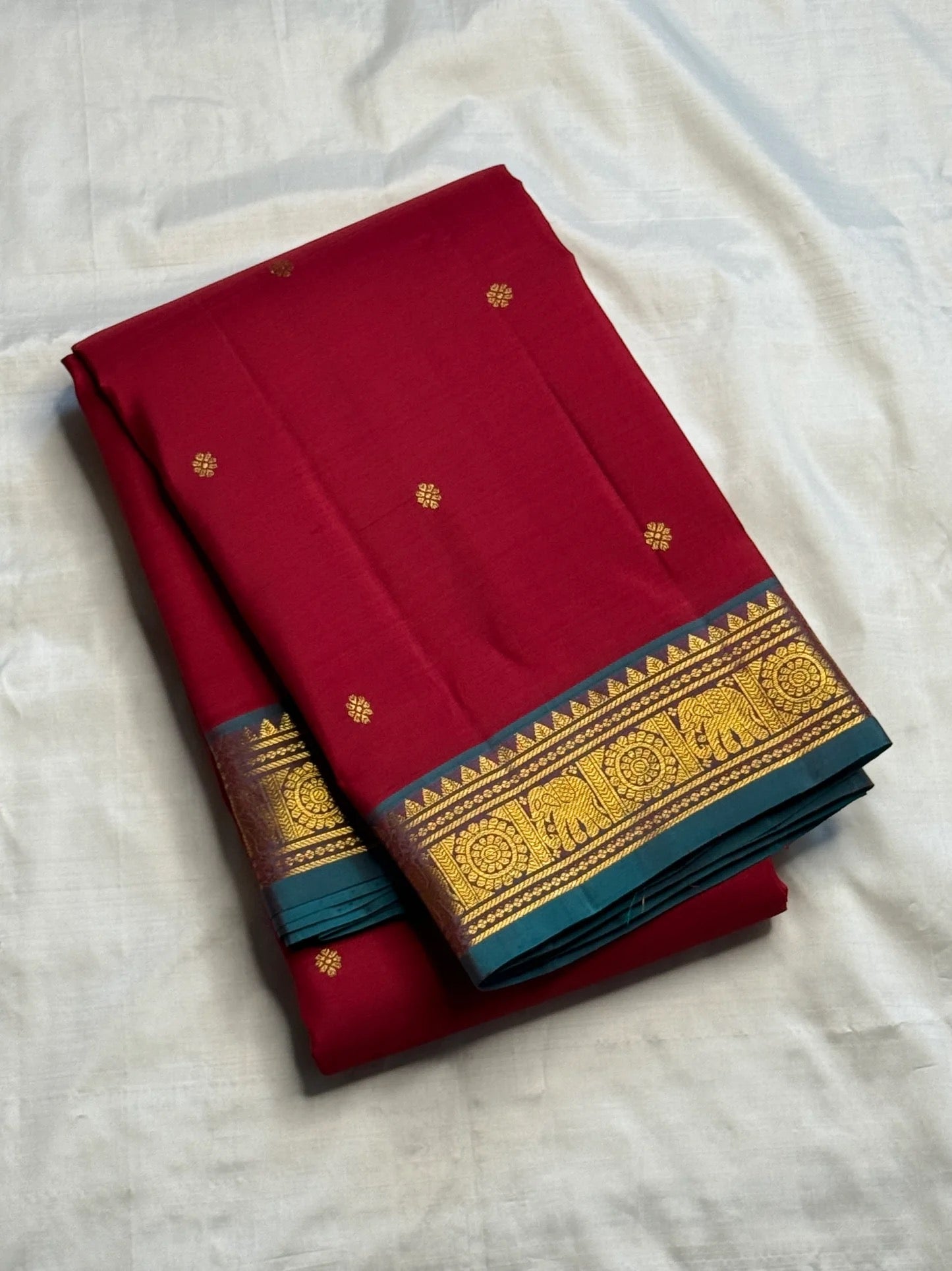 Pallu detail showing teal ground with gold elephant and chakra medallions, maroon Kancheepuram saree