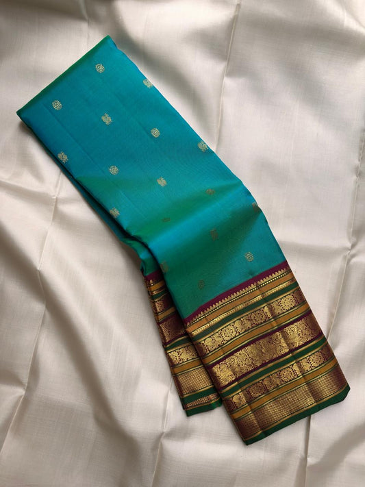 Deep maroon Kanchipuram Varisaipet pallu densely woven with gold zari ornamental columns and rich green accents.