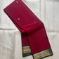 Pure Kanchipuram silk saree folded view showing deep pink body with small gold zari buttas and green contrast border