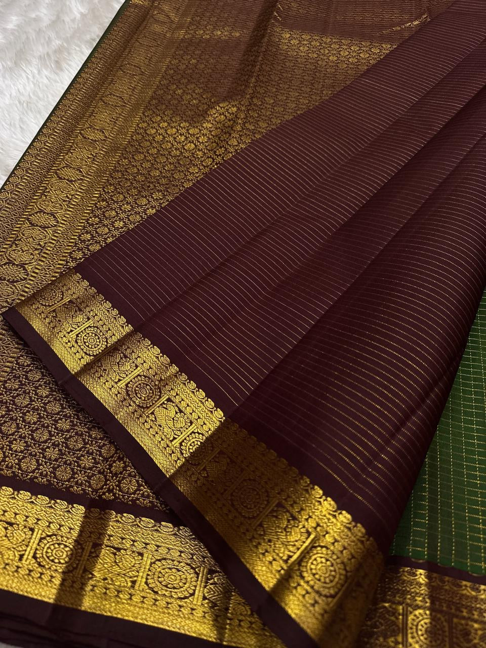 Close view of maroon pallu on a Pure Kanchipuram Silk Saree with fine zari lines and gold zari border featuring traditional motifs.