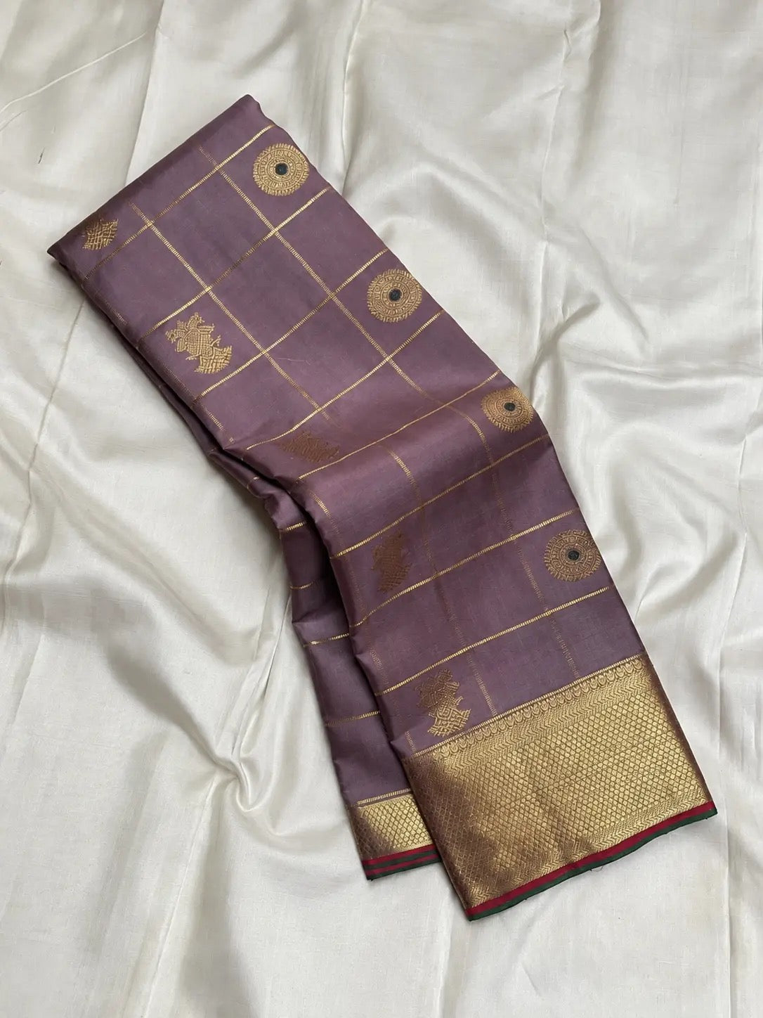 Mauve brown Kanchipuram silk saree with intersecting gold Zari Kattam lines and traditional buttas.