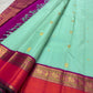 Close view of alternating Mayil and petite Kamalam gold-zari buttas across the mint silk body.