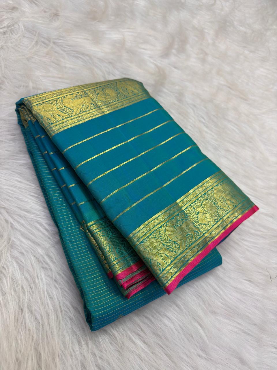 Close view of antique-gold traditional zari motifs woven on blue-green Kanjivaram silk.