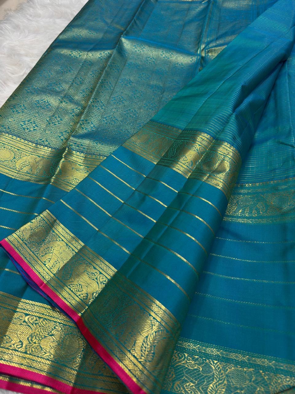 Peacock blue-green Kanchipuram silk saree with fine gold detailing and spaced zari motifs.
