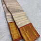 Pavun coin motif and geometric latticework detail, burnt terra-cotta border, warm-ivory Kanjipuram Korvai saree