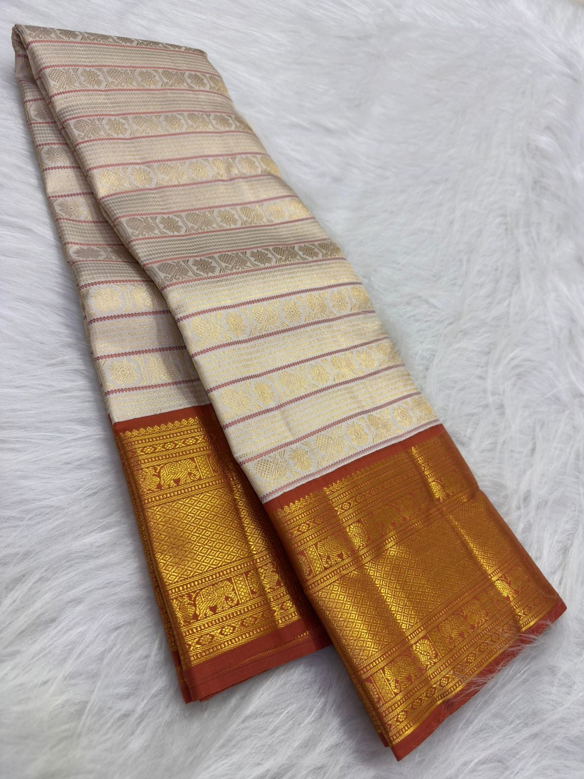 Pavun coin motif and geometric latticework detail, burnt terra-cotta border, warm-ivory Kanjipuram Korvai saree