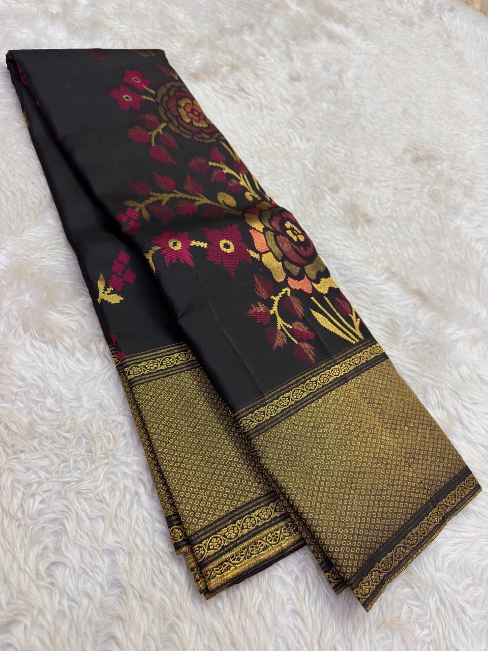 Handwoven black Kanchipuram Butta saree with burgundy peach sage and gold floral zari work.